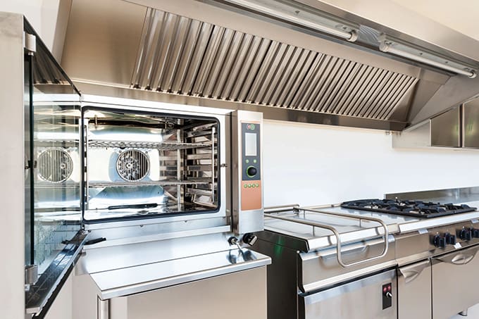 A kitchen with many appliances and stainless steel counters.