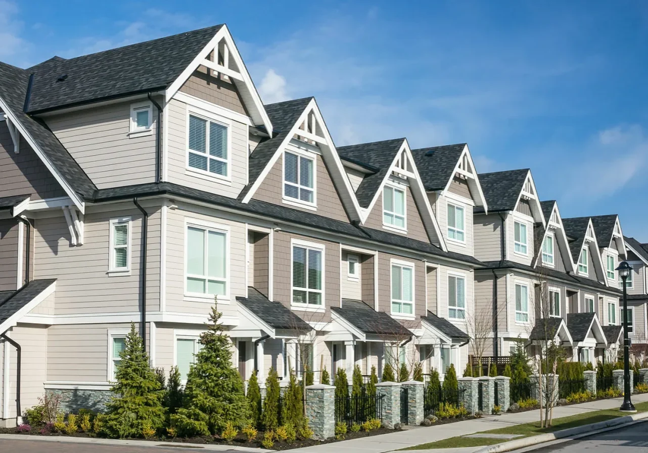 A row of houses with trees in front.